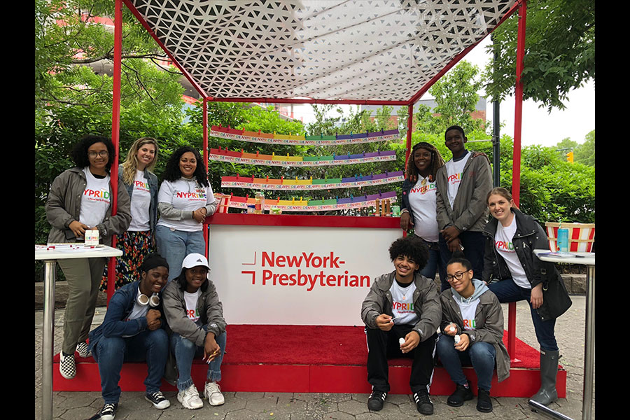 A group of poeple posing for a photo with the NewYork-Presbyterian display