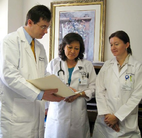A group of doctors wearing white lab coatings looking at a document together