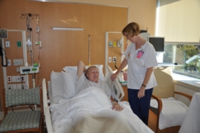 a woman standing next to a man lying in a hospital bed