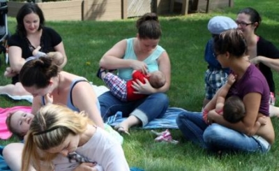 a group of mothers with baby sitting in the grass