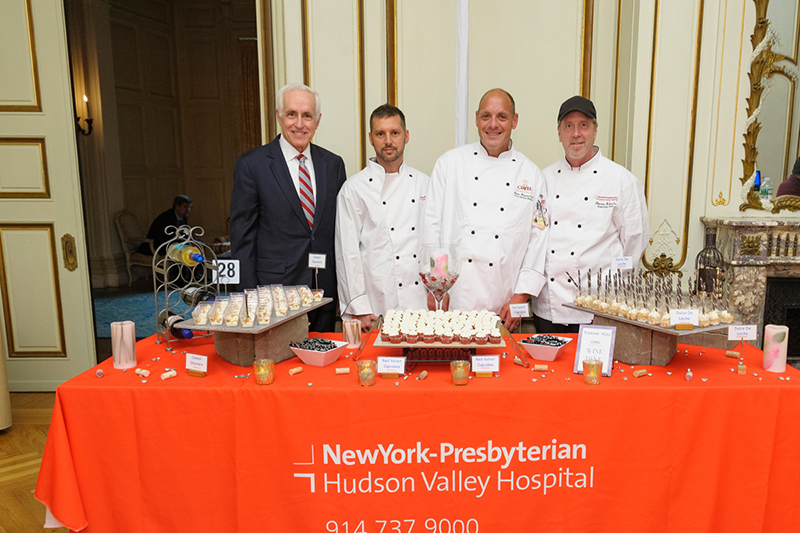a group of men in white coats standing next to a table with food
