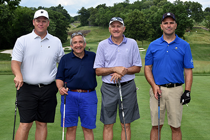 A group of four men posing for a photo on the golf course