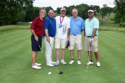 A group of five men posing for a photo on the golf course