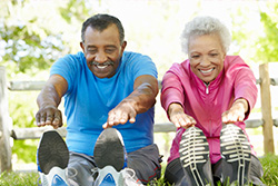 man and woman sitting down reaching their toes