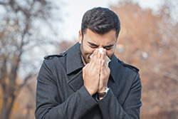 a guy sneezing in a napkin