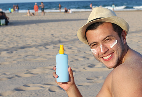 Man holding sunscreen and smiling at camera