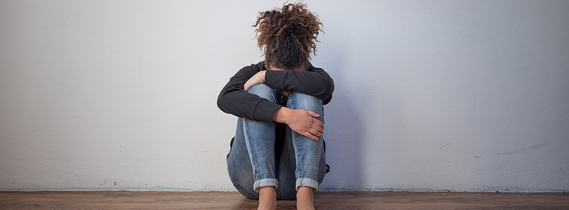 person sitting on floor with head in lap