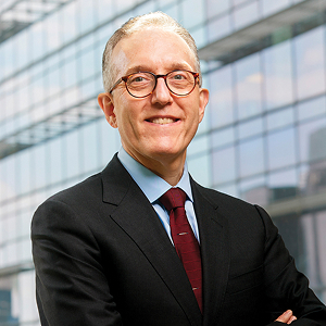 a tall man with glasses smiling straight ahead at viewer