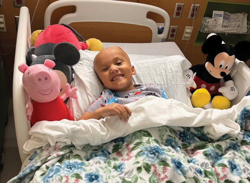 A child in a hospital bed, surrounded by stuffed animals