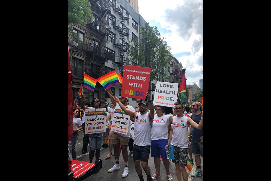 a group of people marching holding NewYork-Presbyterian signs at pride parade