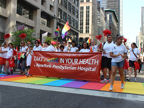 Group of people marching with a banner that says Take PRIDE in your Health | NewYork-Presbyterian
