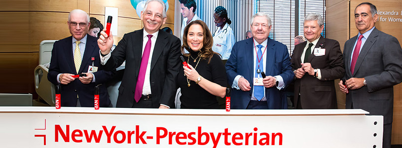 A group of people standing behind a NewYork-Presbyterian sign