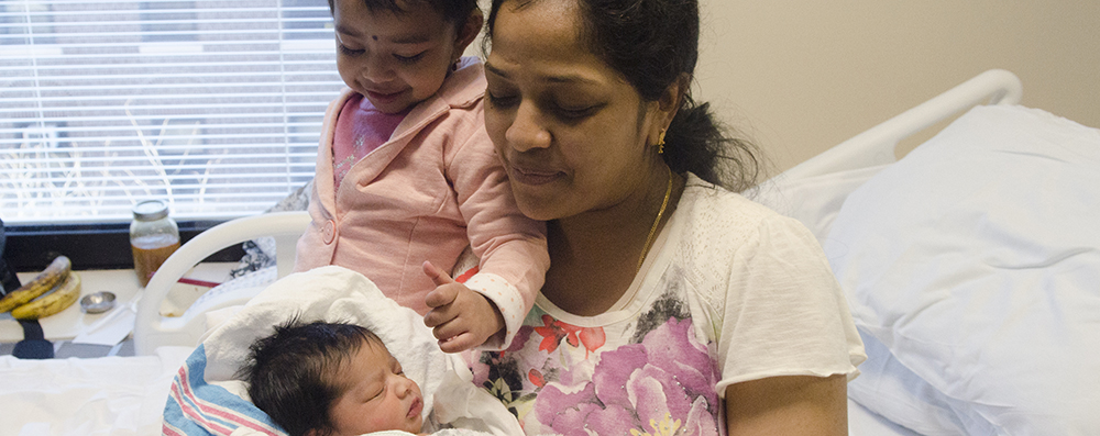 A mother and her child hold her newborn