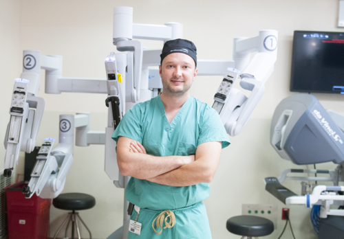 A human surgeon posing for a photo in front of a robotic surgeon