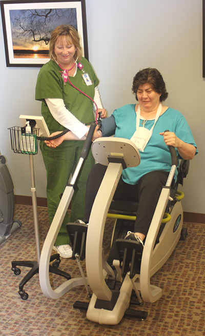 Nurse helping patient use exercise equipment
