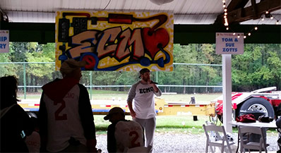 Person with a microphone speaking under a pavilion