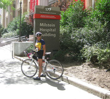 Pamela Abma riding her bike in front of Milstein Hospital Building