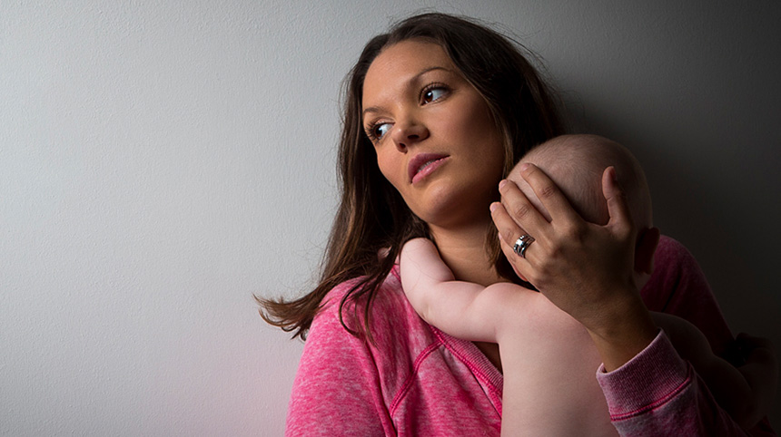 Distressed mother with signs of postpartum depression holding infant