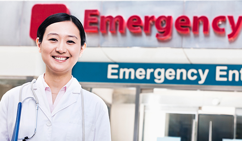 image of doctor standing in front of emergency sign and doors