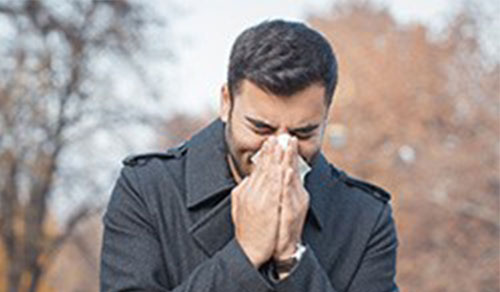 man sneezing into a napkin