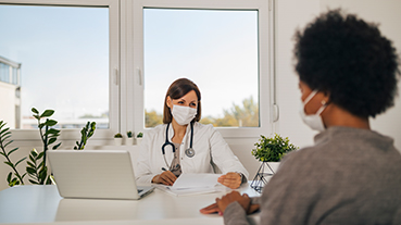 image of doctor and patient wearing masks talking