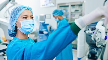 image of a surgical assistant turning on equipment in an operating room