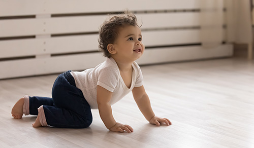toddler baby child crawling on warm wooden home floor
