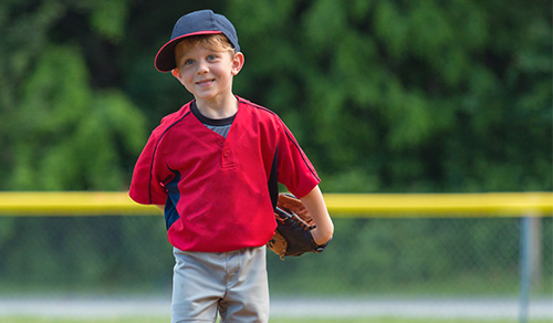image of a little boy smiling on the field during a baseball game