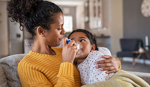 mother holding daughter making inhalation with a nebulizer