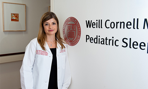 Dr. Haviva Veler standing next to Weill Cornell sign on the wall