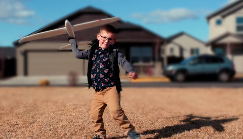 little boy throwing toy airplane