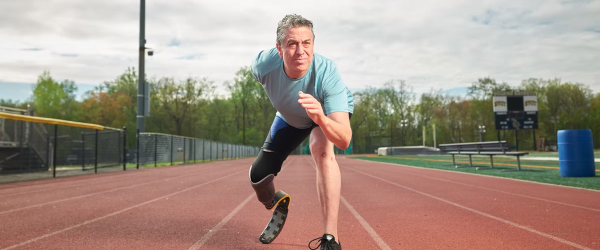 Image of Gary Yerman, who underwent a leg amputation, poised on a track preparing to run.