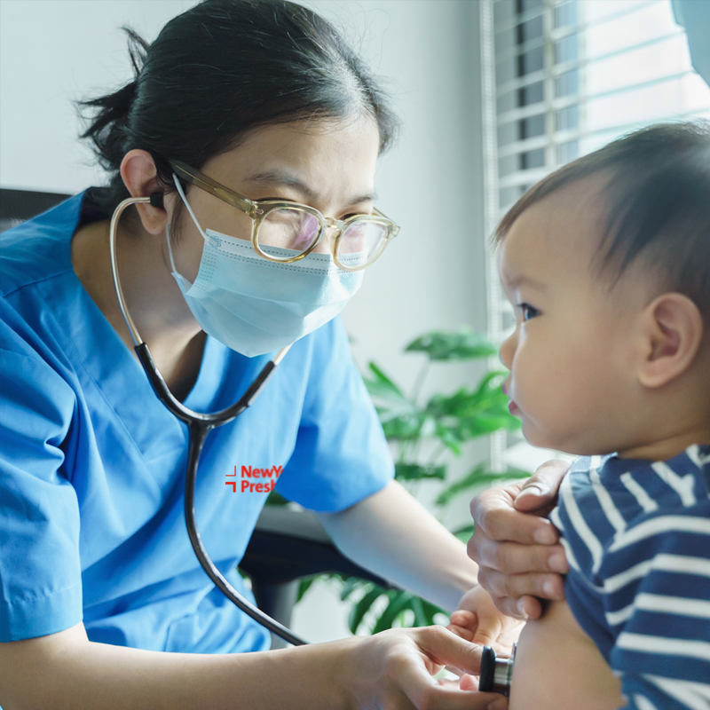 Asian clinician using a stethoscope on a toddler