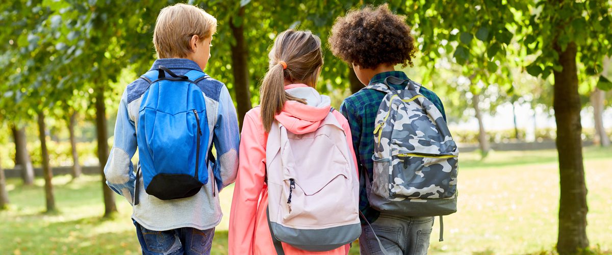 A group of children walking with their backpacks on.