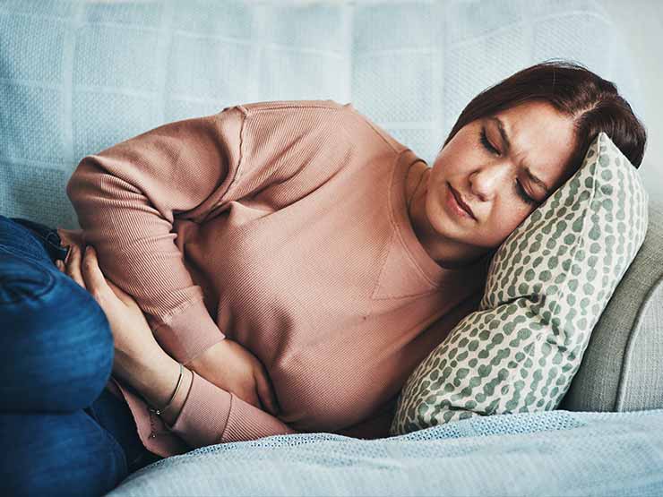 image of girl holding stomach in pain on the couch