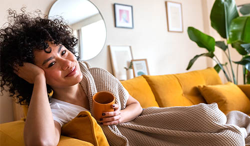 female holding cup sitting on couch