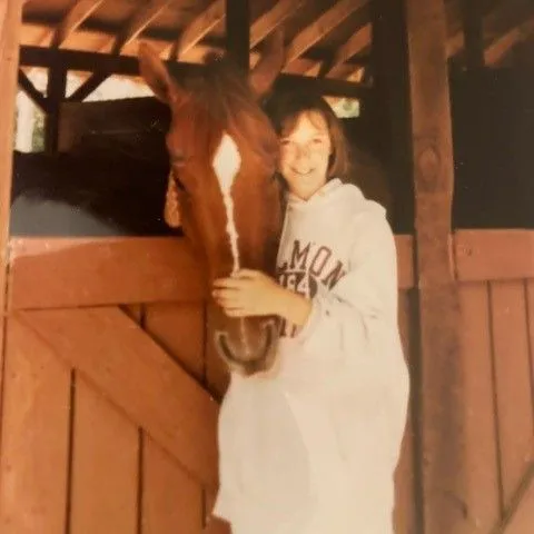 Dr. Hoffman standing next to horse smiling.