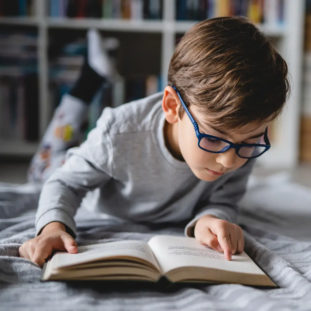 A child with glasses reading a book.