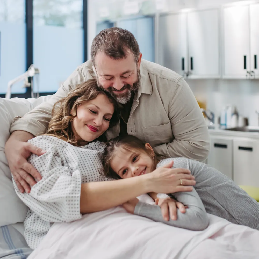 A family hugging each other in a medical exam room.