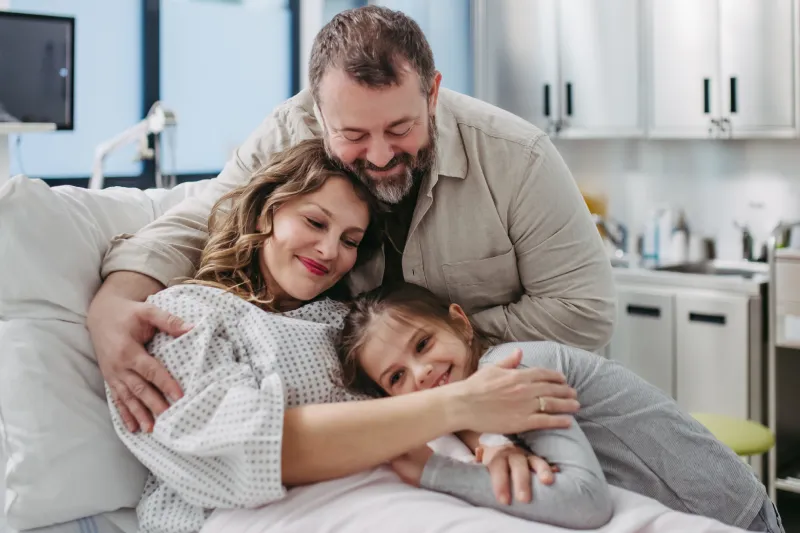 A family hugging each other in a medical exam room.