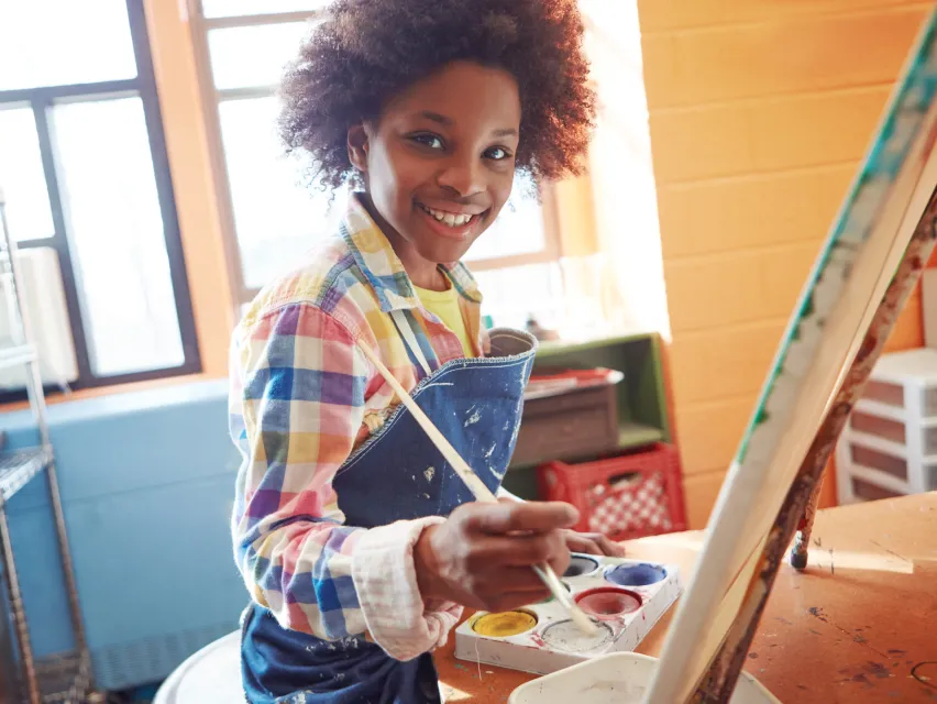 A young boy painting on a canvas.