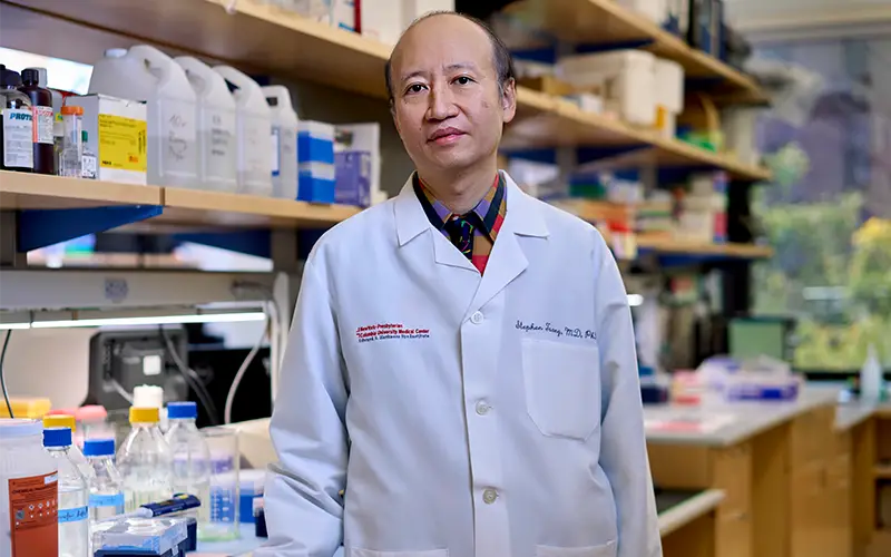 Dr. Tsang in a white lab coat in a scientific lab at Columbia.