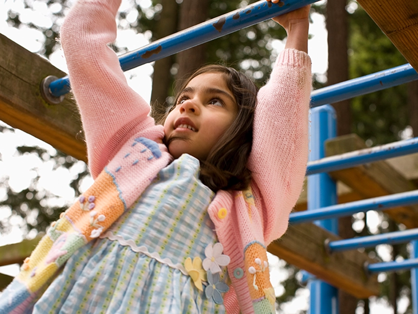 young girl playing on monkey bars