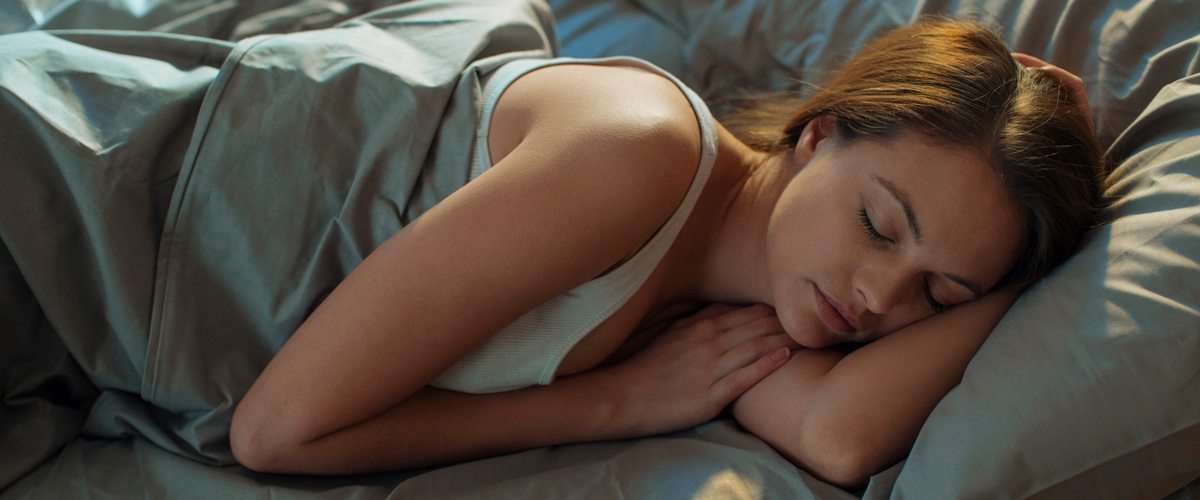 A woman sleeping on green sheets