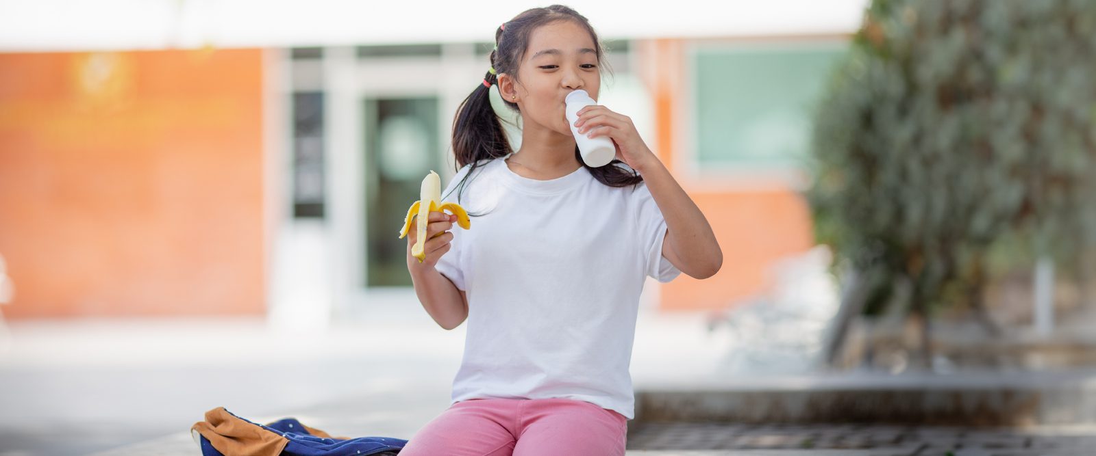 Girl drinking milk and eating a banana