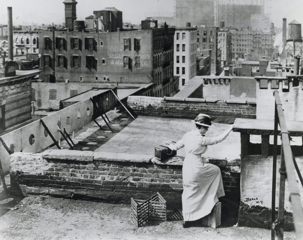 image of A nurse from the Henry Street Settlement climbs a tenement roof.
