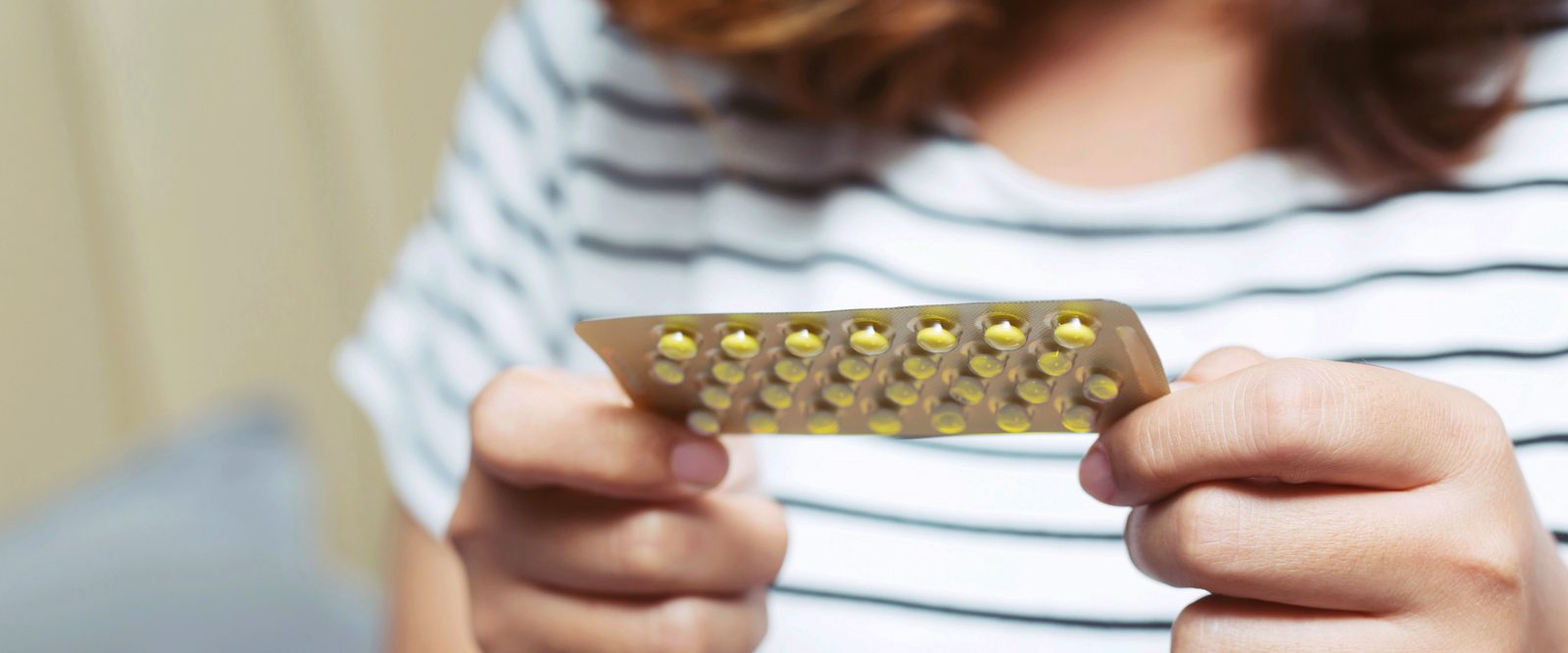 Woman holding a set of birth control pills