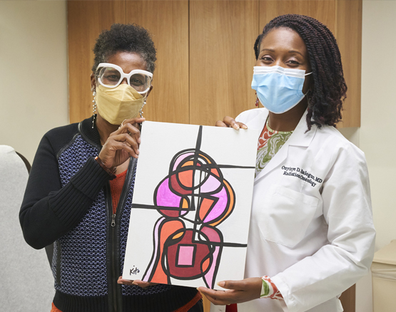 Julia Kito Kirtley and her radiation oncologist, Dr. Onyinye Balogun, with Kirtley’s art.