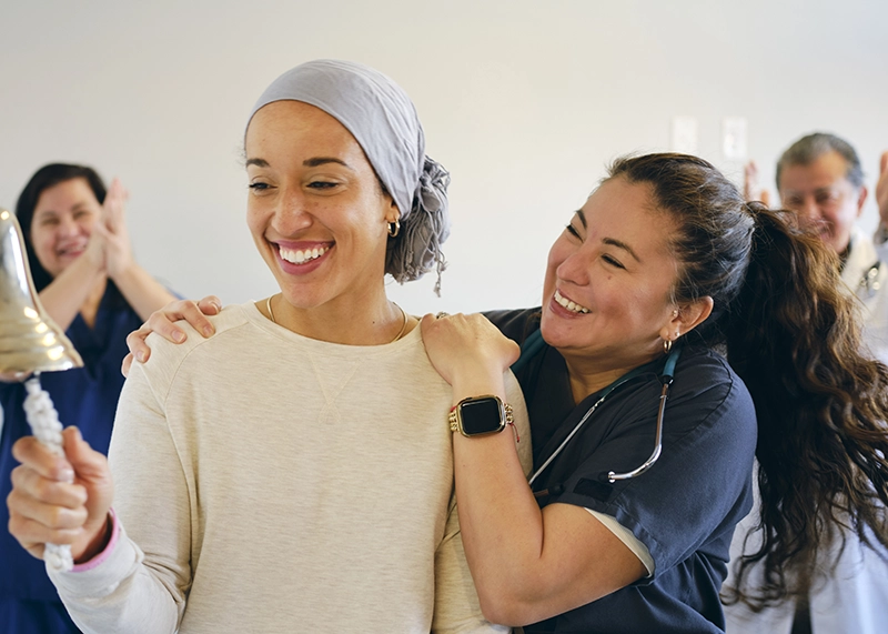 Cancer patient ringing a bell with her care team to celebrate the end of chemo treatment.