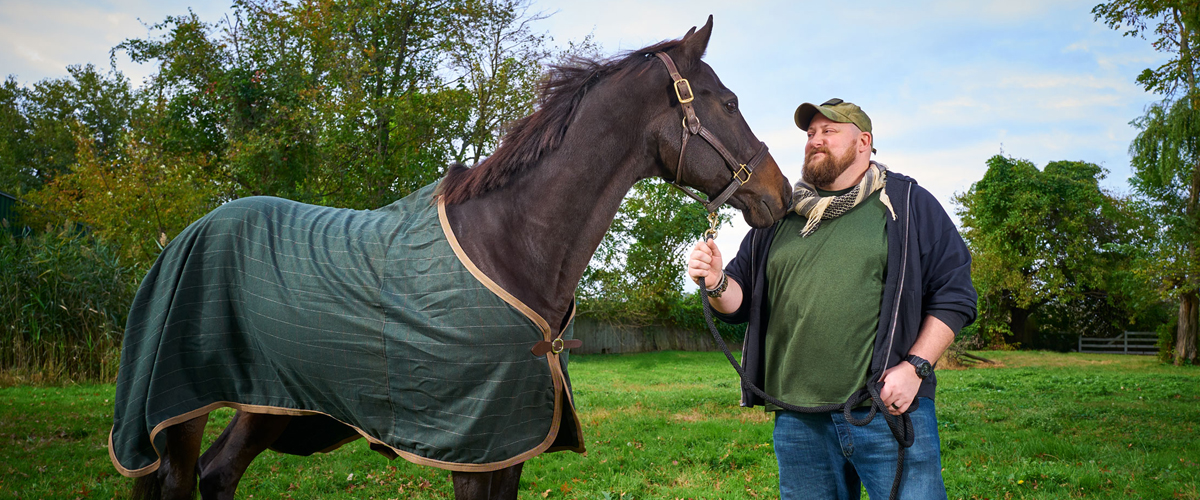 A man holding the reins of a horse next to him.